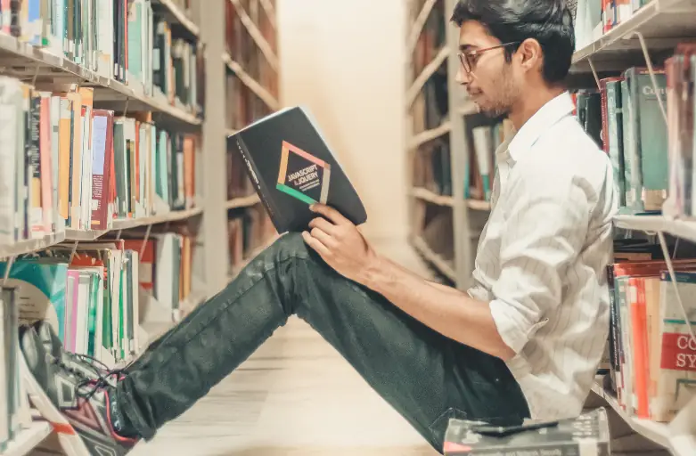 Étudiant lisant un livre dans une bibliothèque